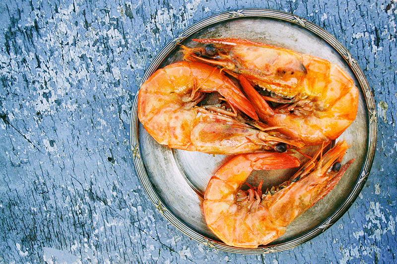a plate of shrimp on a blue surface